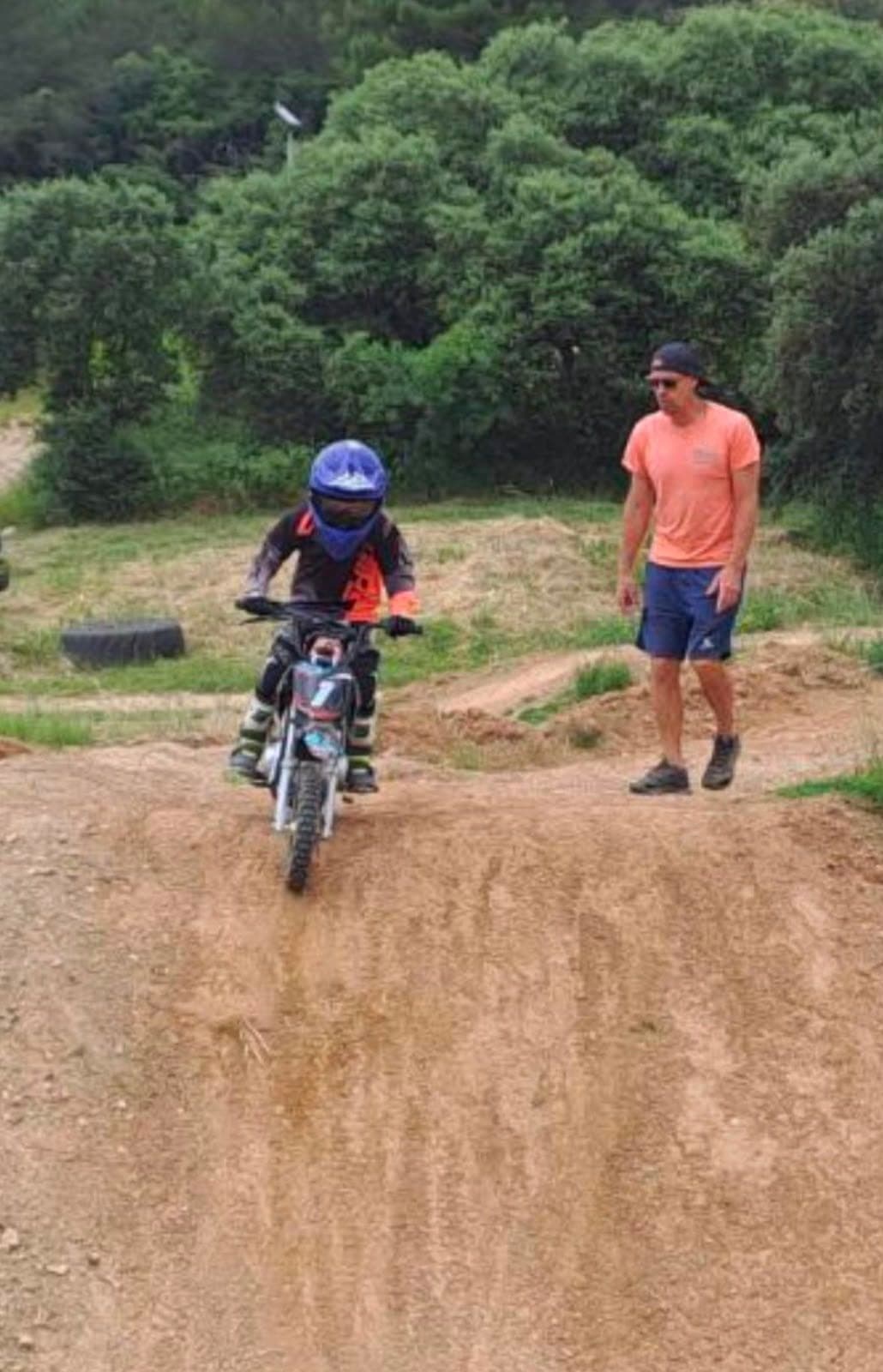 Un jeune enfant fait ses premiers tours de roue en moto sous le regard du moniteur